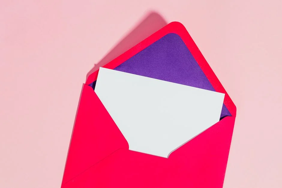 Vue à plat de touches de clavier formant le mot email sur un fond corail.